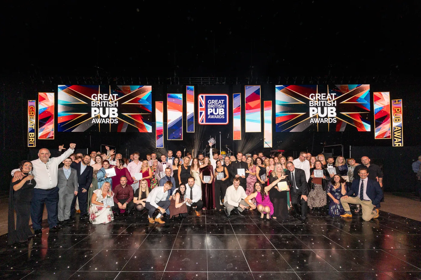 Winners from the Great British Pub Awards 2026 cheering and raising their arms in front of the stage screens
